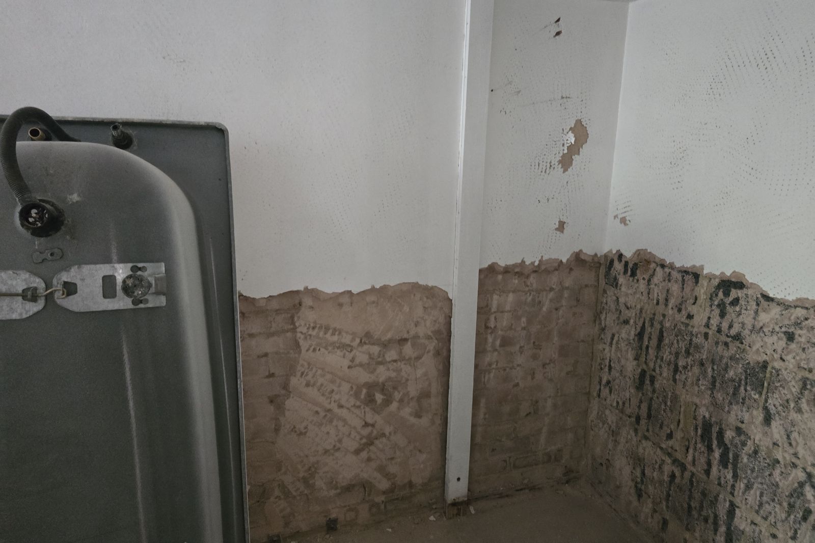 Plaster stripped back to brickwork after an escape of water in a flat