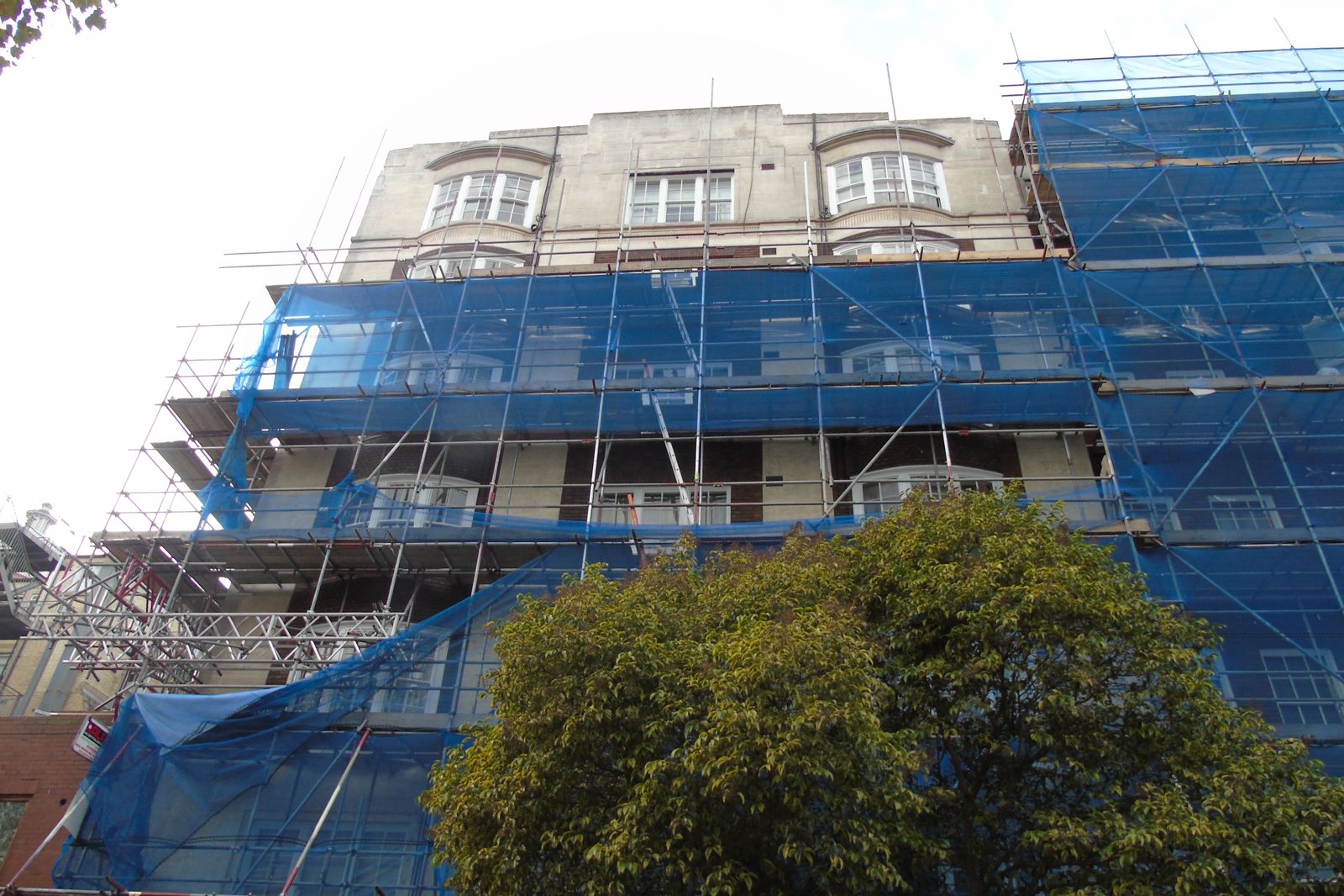 Stone dressed upper floors under scaffold during external repairs